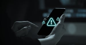 A mobile phone displaying alert signs, indicating the use of an AI-driven SCAMBlock solution to block spam and robocalls